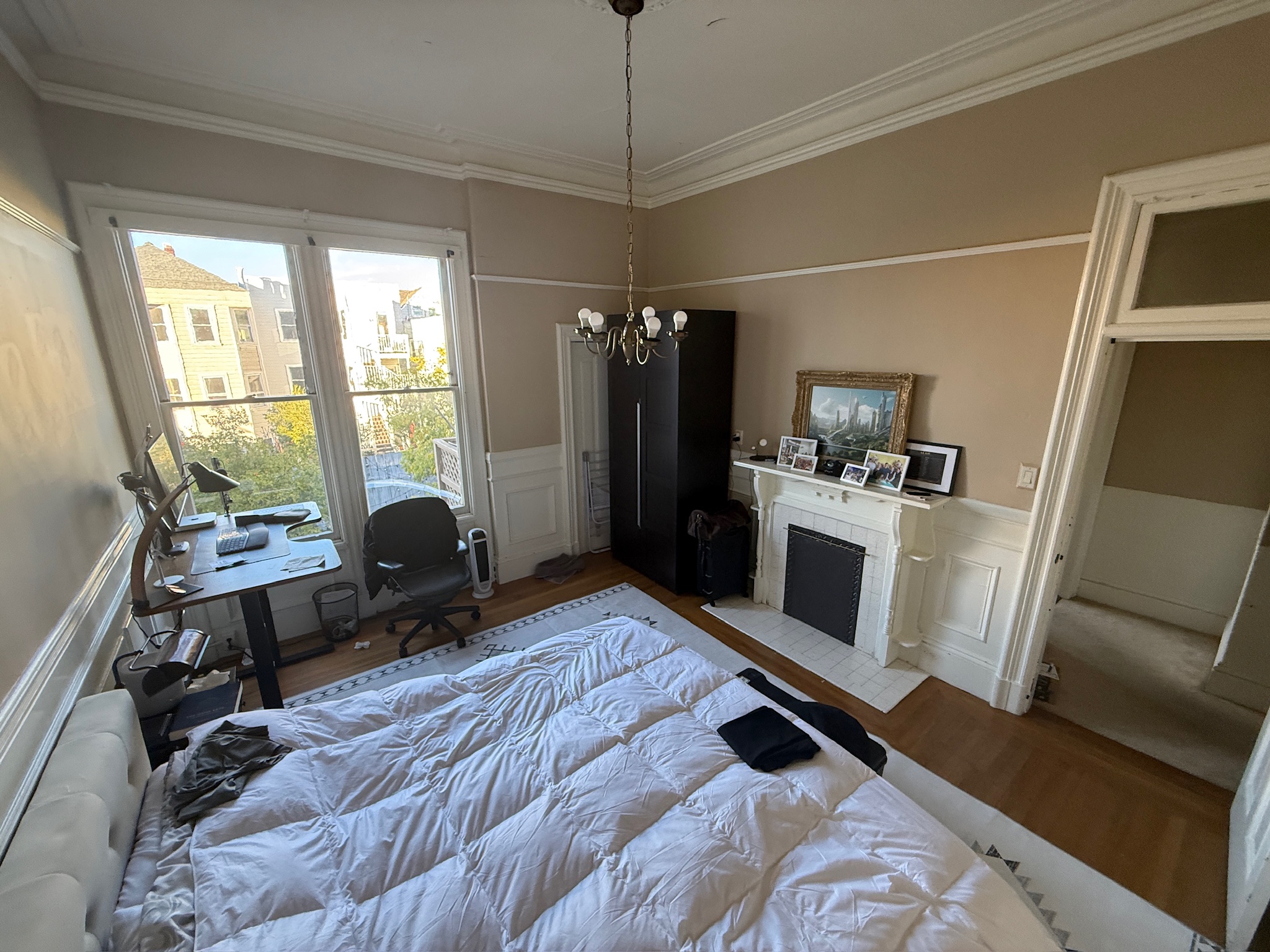 Large bedroom with city view windows and chandelier